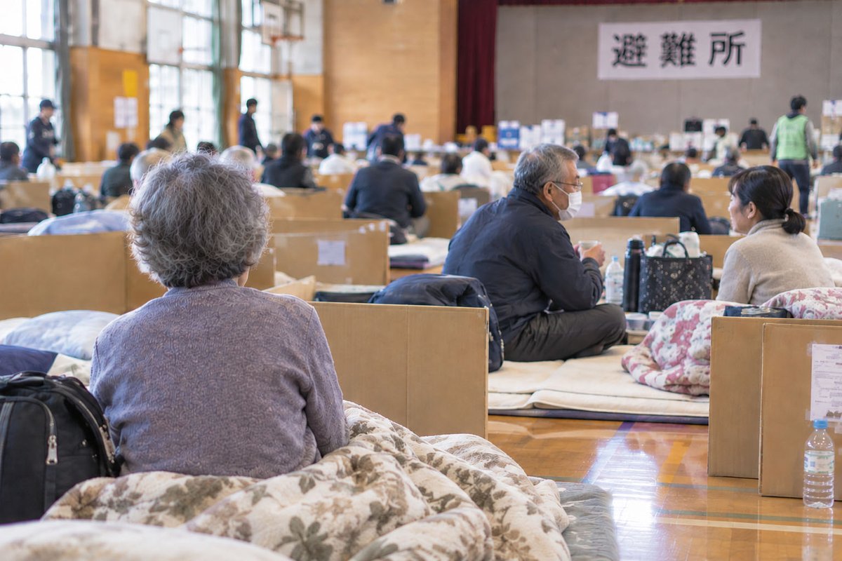 体育館の床の上で避難生活を送る高齢者のイメージ